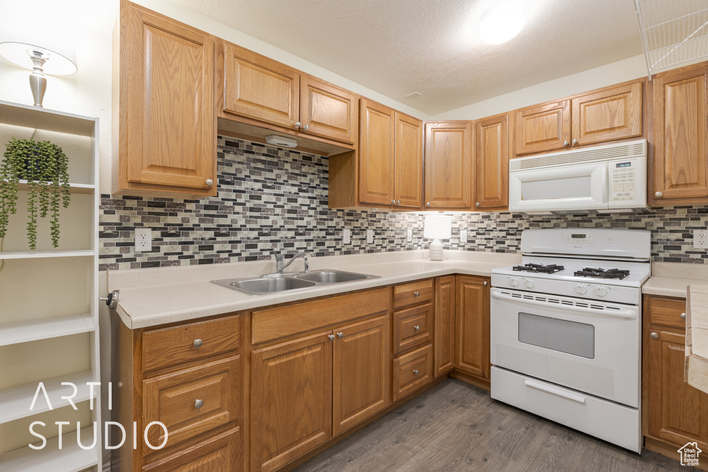 Kitchen with a textured ceiling, dark hardwood / wood-style flooring, sink, decorative backsplash, and white appliances