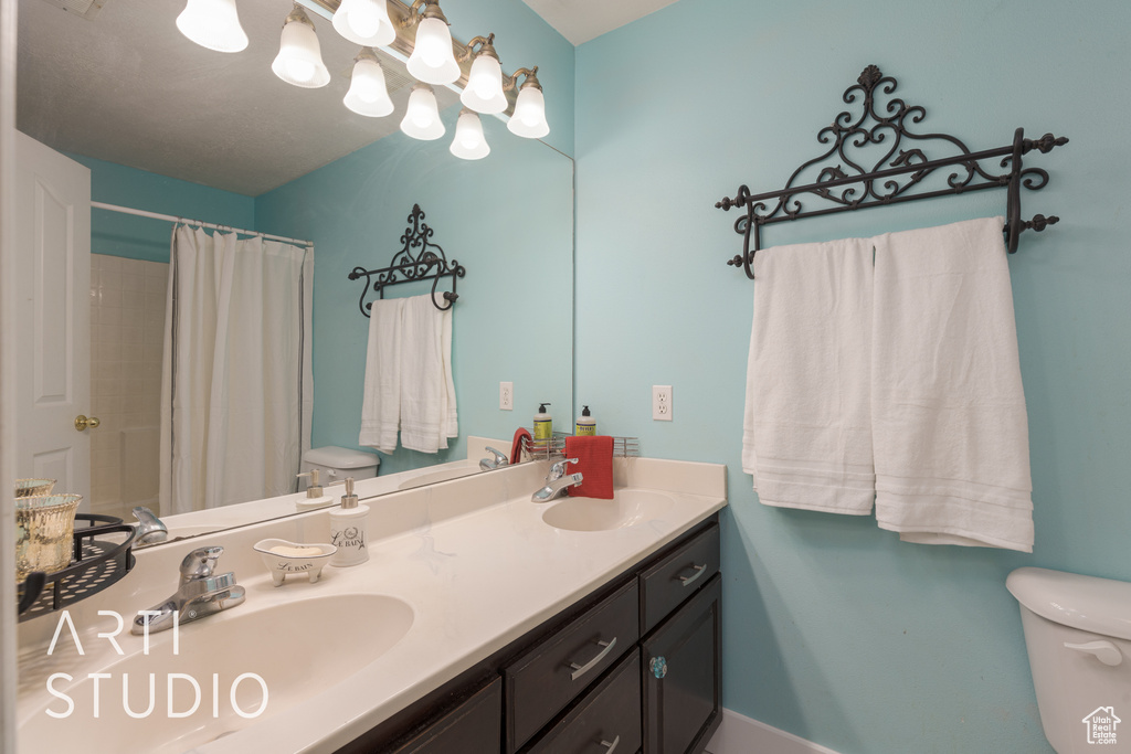 Bathroom featuring walk in shower, vanity, and toilet