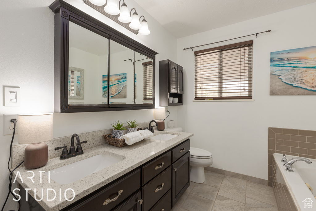 Bathroom featuring tiled bath, tile patterned flooring, vanity, and toilet