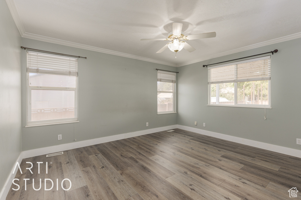 Spare room featuring hardwood / wood-style flooring, ceiling fan, and crown molding