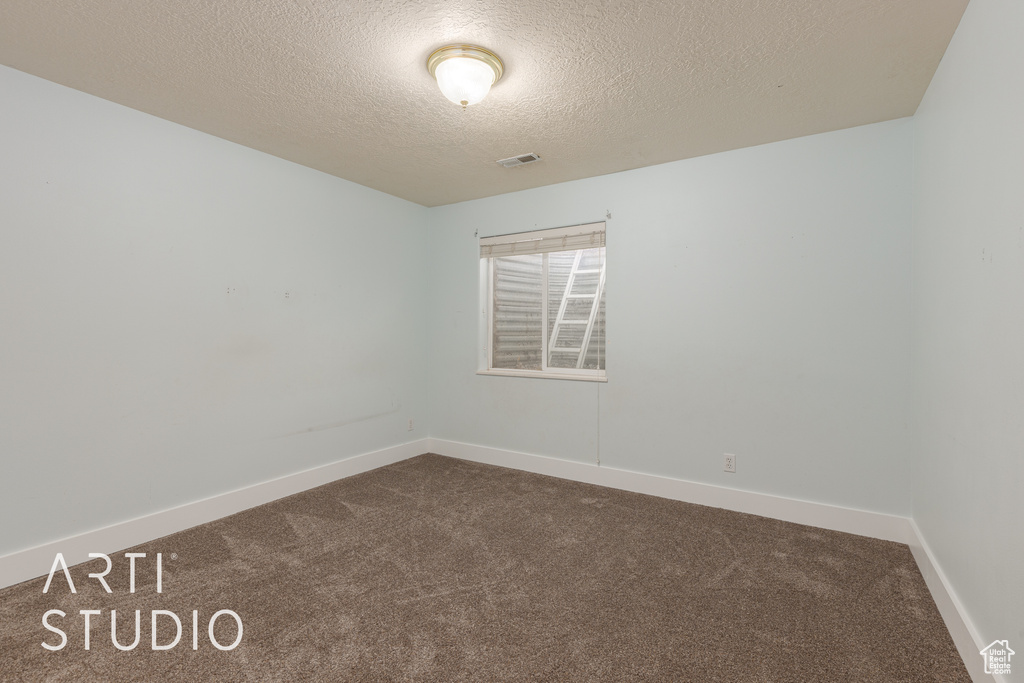 Empty room with a textured ceiling and carpet floors