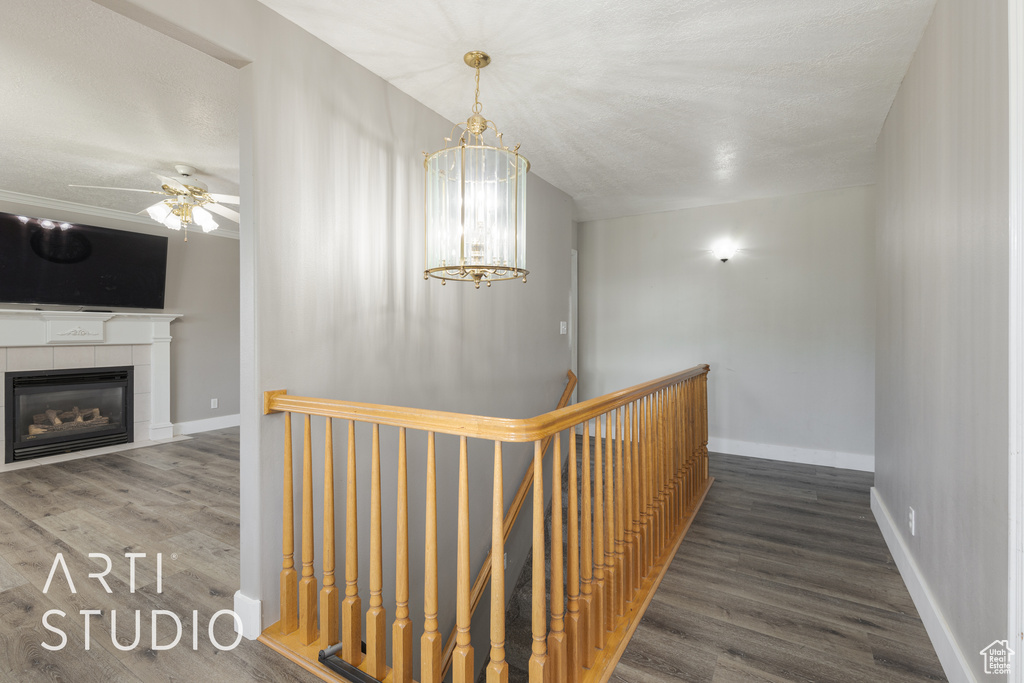 Hallway with a textured ceiling, dark hardwood / wood-style flooring, and a chandelier