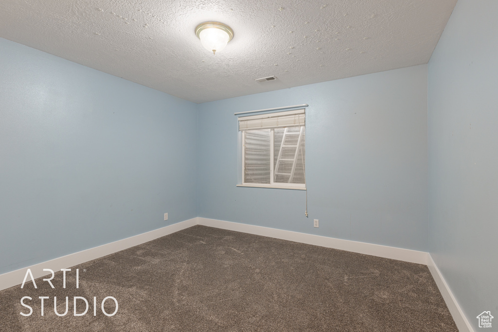 Carpeted empty room featuring a textured ceiling