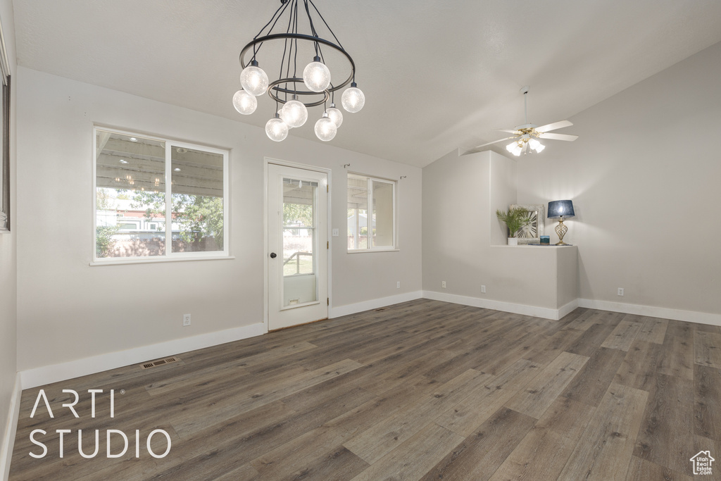 Unfurnished dining area with dark hardwood / wood-style flooring, vaulted ceiling, and ceiling fan with notable chandelier