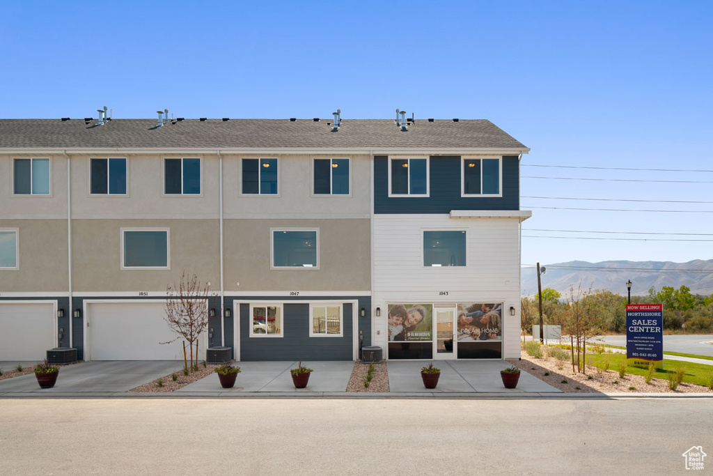 View of building exterior featuring a mountain view, a garage, and central AC