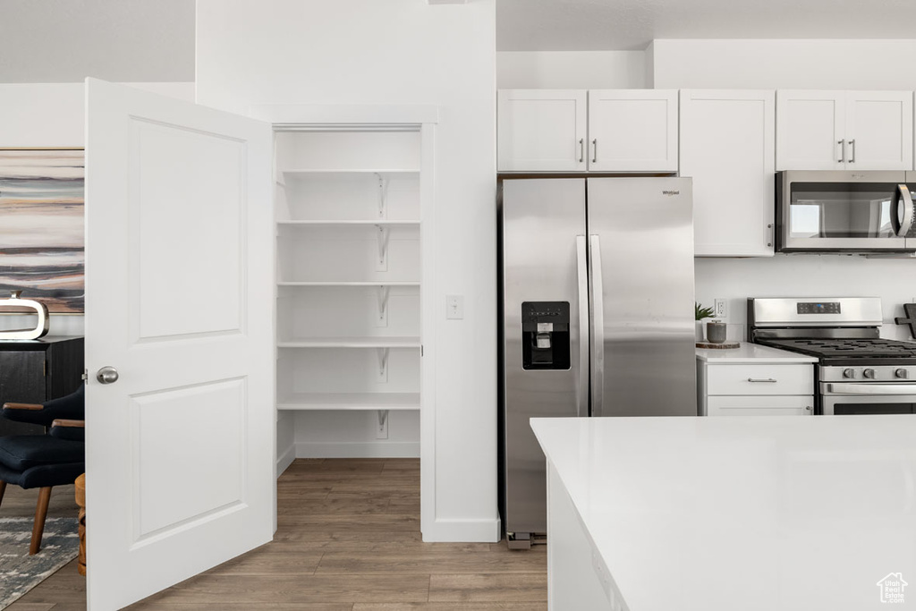 Kitchen with white cabinets, appliances with stainless steel finishes, and light hardwood / wood-style flooring