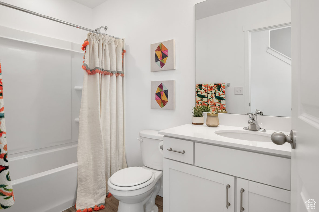 Full bathroom featuring toilet, vanity, wood-type flooring, and shower / bath combo with shower curtain