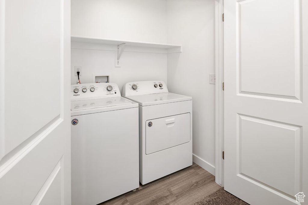 Washroom with light wood-type flooring and independent washer and dryer