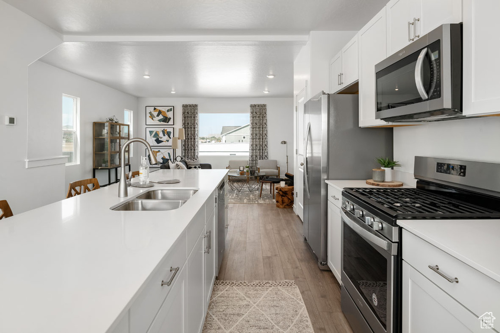 Kitchen featuring white cabinets, sink, light wood-type flooring, and appliances with stainless steel finishes