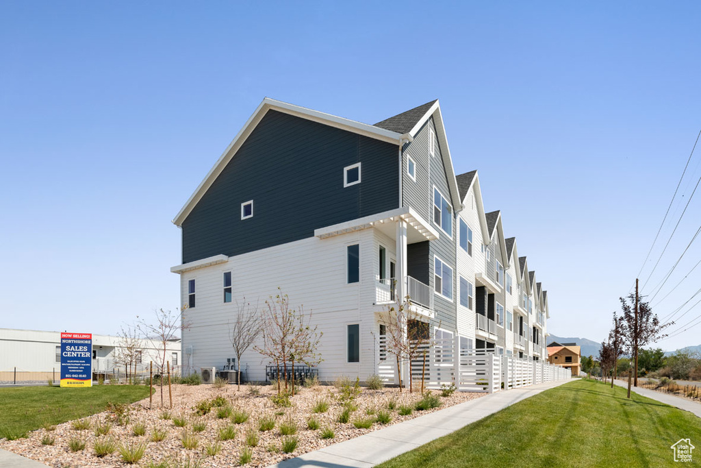 View of side of home featuring a balcony and a yard