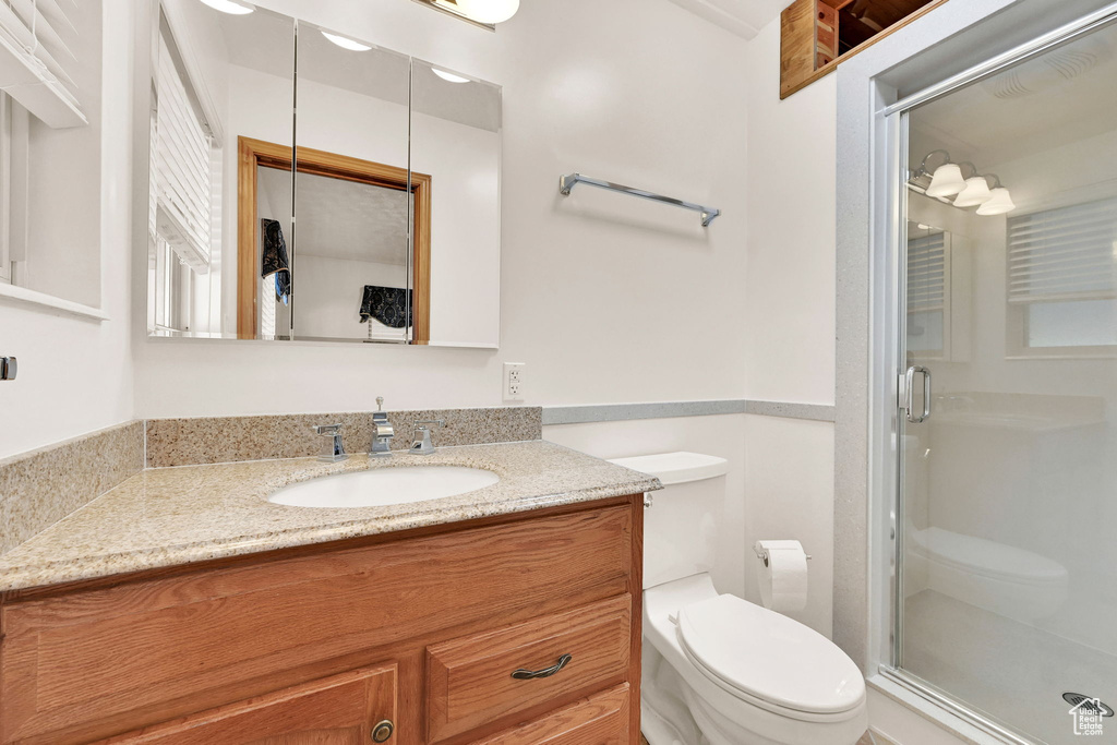 Bathroom featuring vanity, toilet, and a shower with door