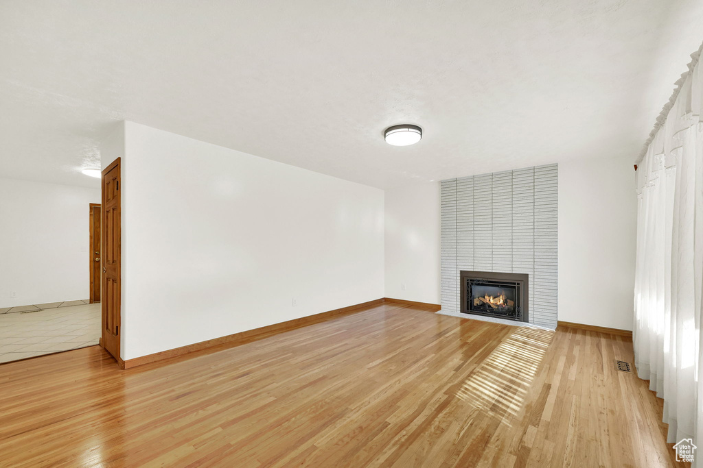 Unfurnished living room featuring a large fireplace and light hardwood / wood-style flooring