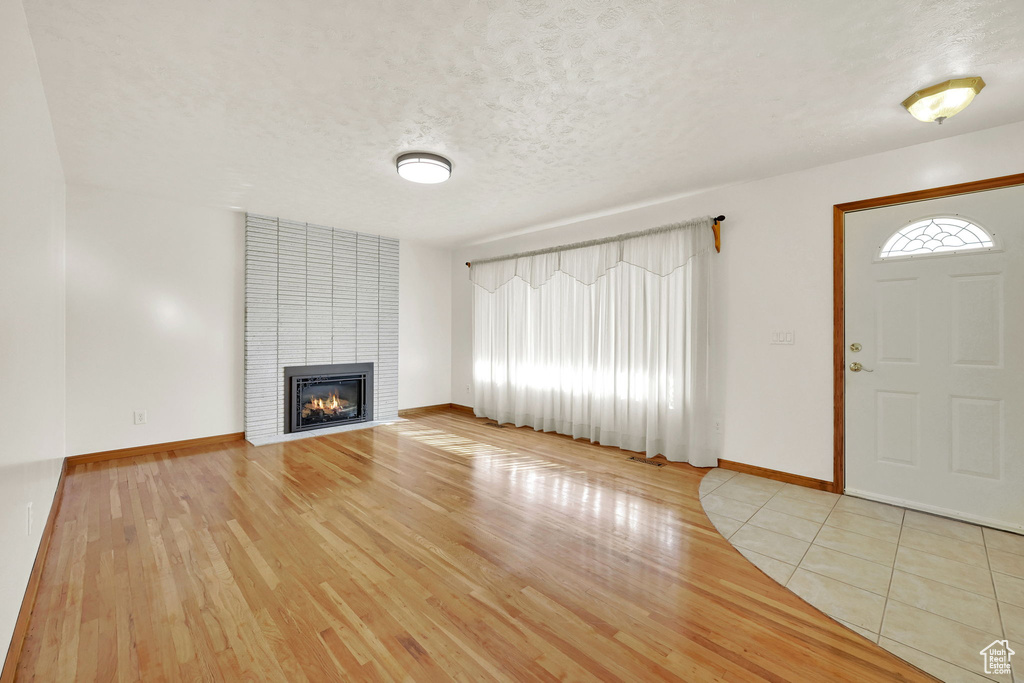 Entryway with a textured ceiling, light hardwood / wood-style floors, and a fireplace