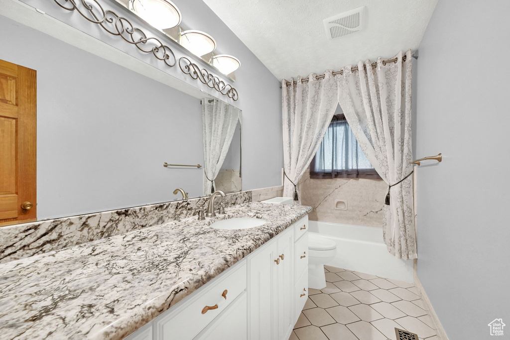 Full bathroom with tile patterned floors, vanity, a textured ceiling, shower / tub combo, and toilet