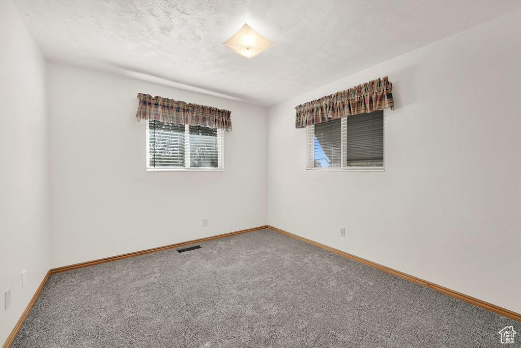 Empty room featuring a textured ceiling and carpet