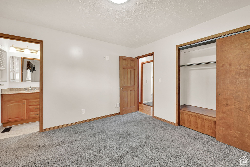 Unfurnished bedroom with a closet, a textured ceiling, and light carpet