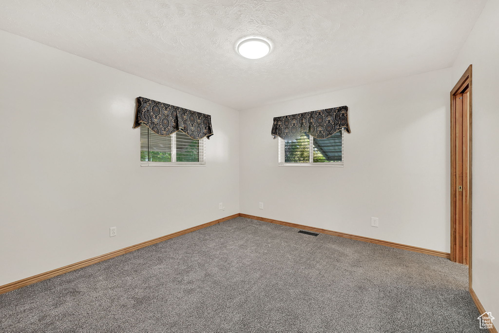 Spare room featuring a textured ceiling and carpet