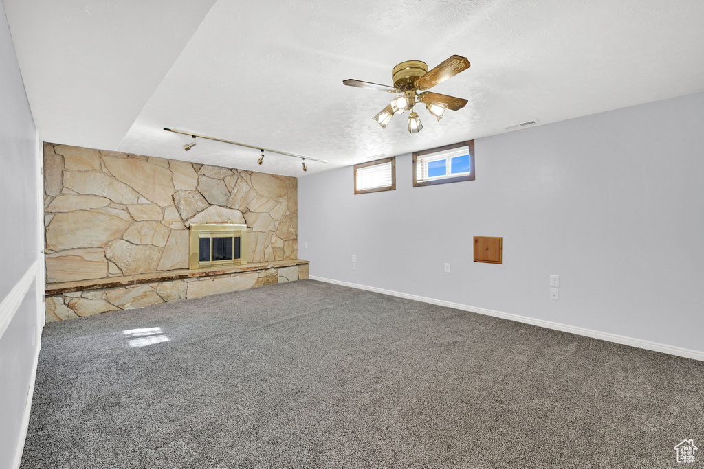 Unfurnished living room featuring carpet, a fireplace, rail lighting, and a textured ceiling