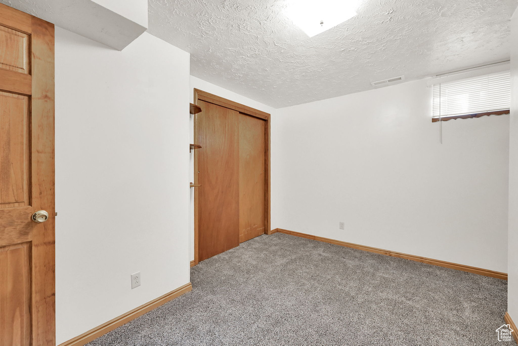 Unfurnished bedroom with a textured ceiling, a closet, and carpet flooring