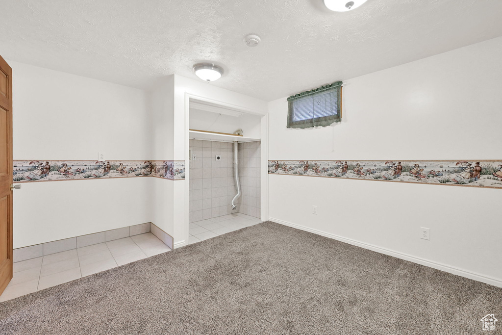 Empty room featuring a textured ceiling and light carpet