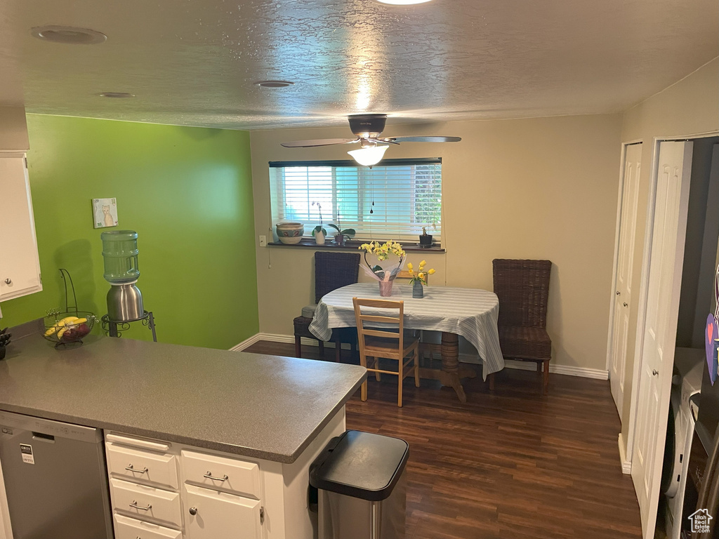 Kitchen featuring stainless steel dishwasher, a ceiling fan, white cabinetry, dark wood-style flooring, and baseboards