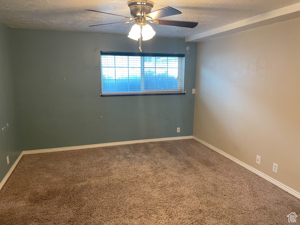 Unfurnished room featuring a textured ceiling, carpet flooring, ceiling fan, and baseboards