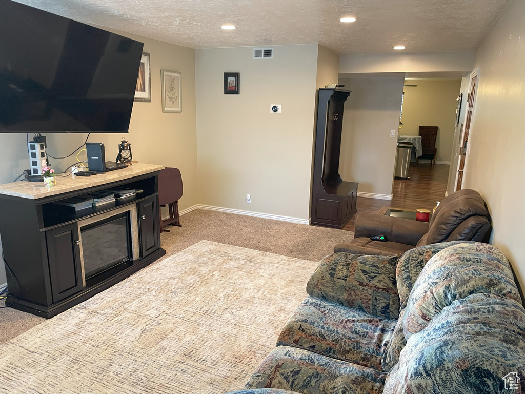Living area featuring light carpet, a textured ceiling, baseboards, and recessed lighting