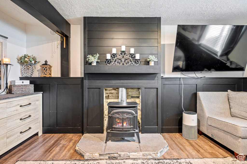 Interior space with hardwood / wood-style floors, a textured ceiling, and a wood stove