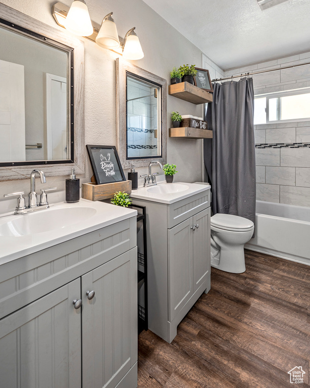 Full bathroom featuring wood-type flooring, toilet, a textured ceiling, vanity, and shower / bath combination with curtain