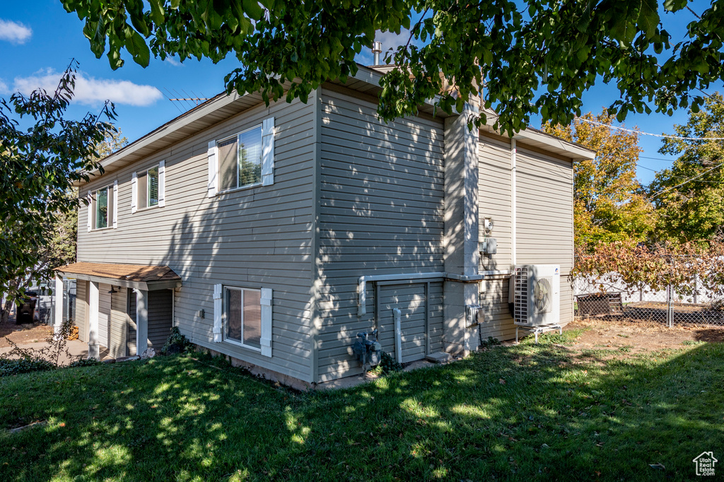 View of side of home featuring ac unit and a yard