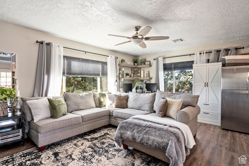 Living room featuring a textured ceiling, dark wood-type flooring, and ceiling fan