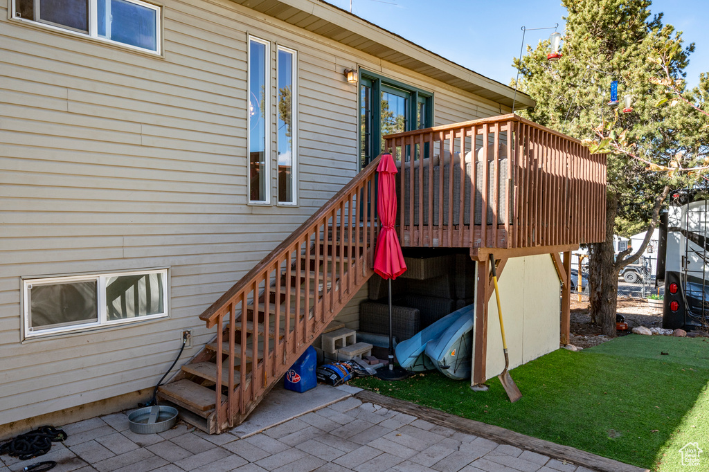 Entrance to property with a patio, a lawn, and a wooden deck