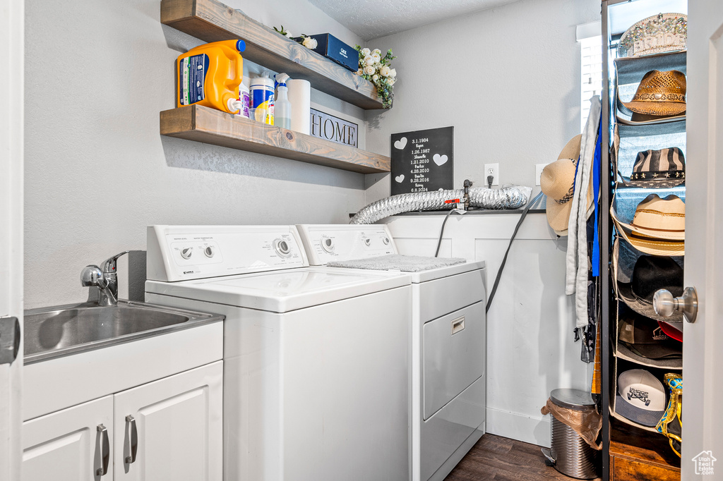 Washroom with washer and clothes dryer, a textured ceiling, dark hardwood / wood-style flooring, cabinets, and sink