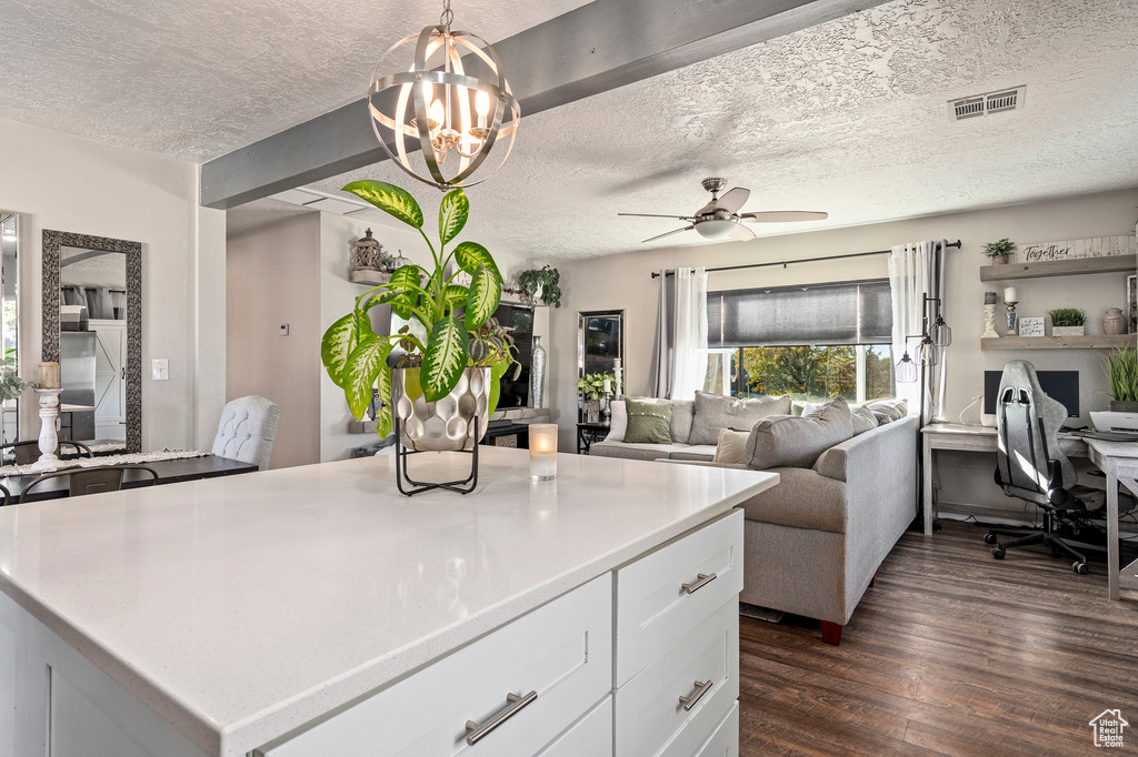 Kitchen featuring a textured ceiling, pendant lighting, white cabinets, dark wood-type flooring, and ceiling fan with notable chandelier