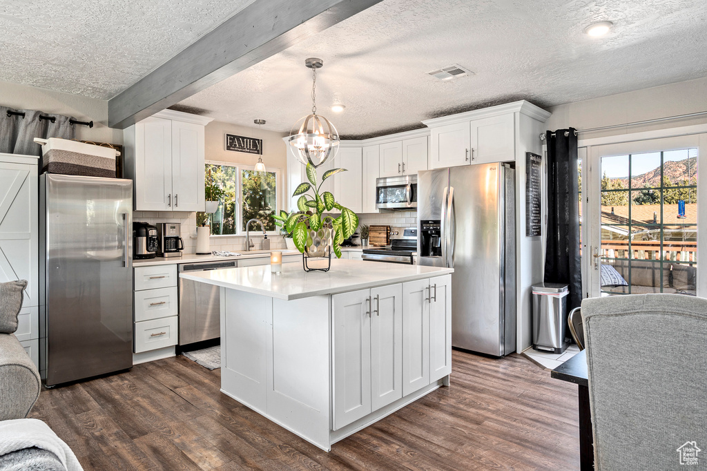 Kitchen with white cabinetry, decorative light fixtures, dark hardwood / wood-style floors, and stainless steel appliances