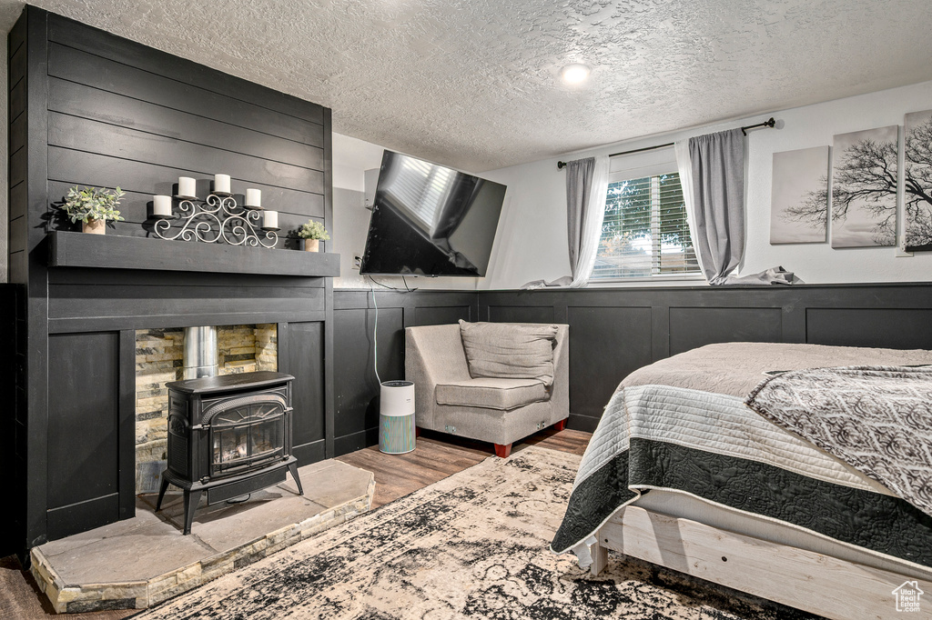 Bedroom featuring a wood stove, hardwood / wood-style flooring, and a textured ceiling