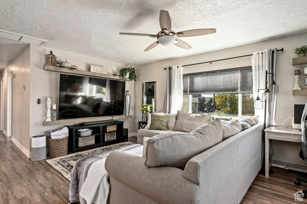 Living room with dark wood-type flooring, ceiling fan, and a textured ceiling