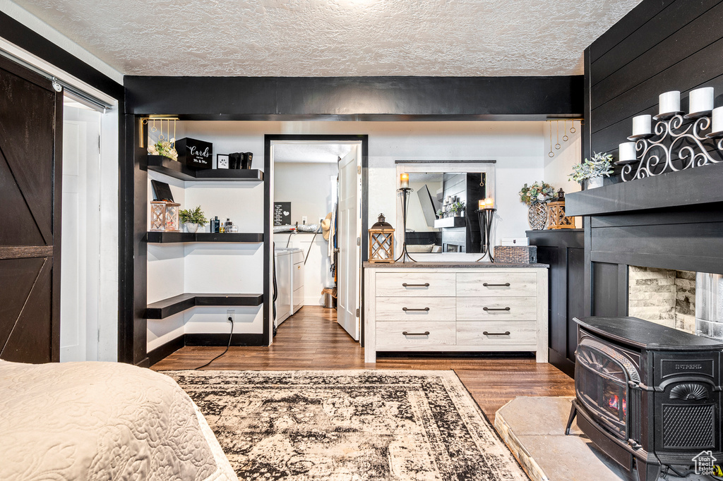 Bedroom with a wood stove, wood-type flooring, and a textured ceiling