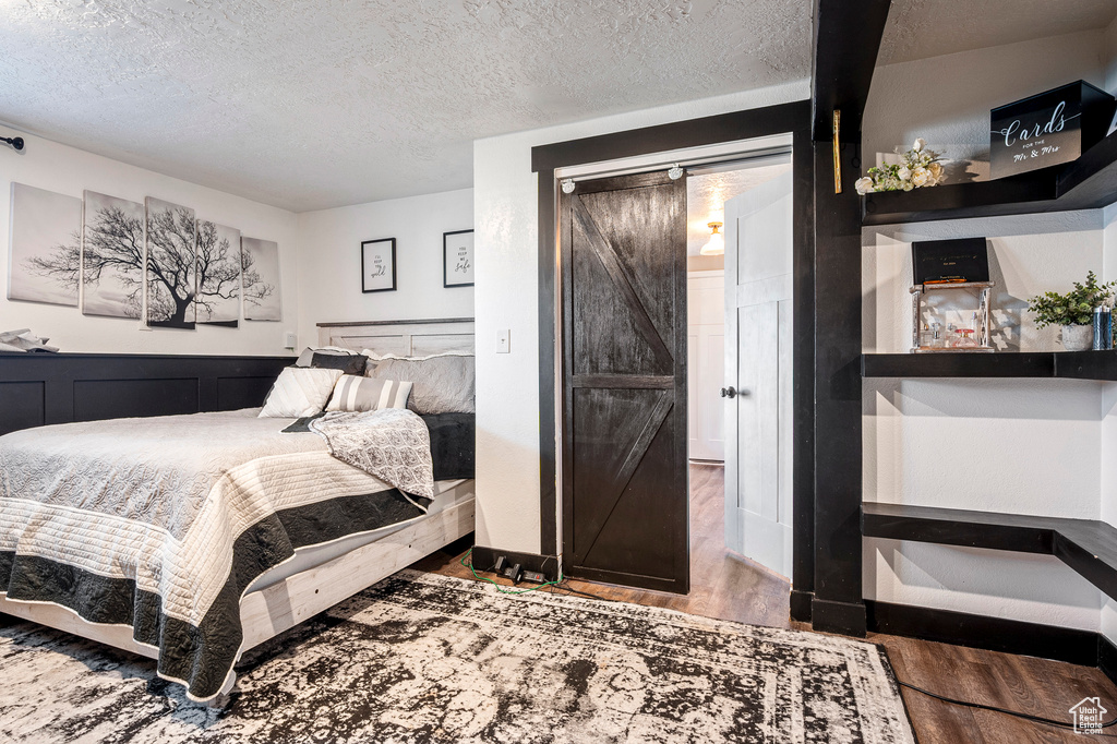 Bedroom featuring a barn door, a textured ceiling, and hardwood / wood-style floors