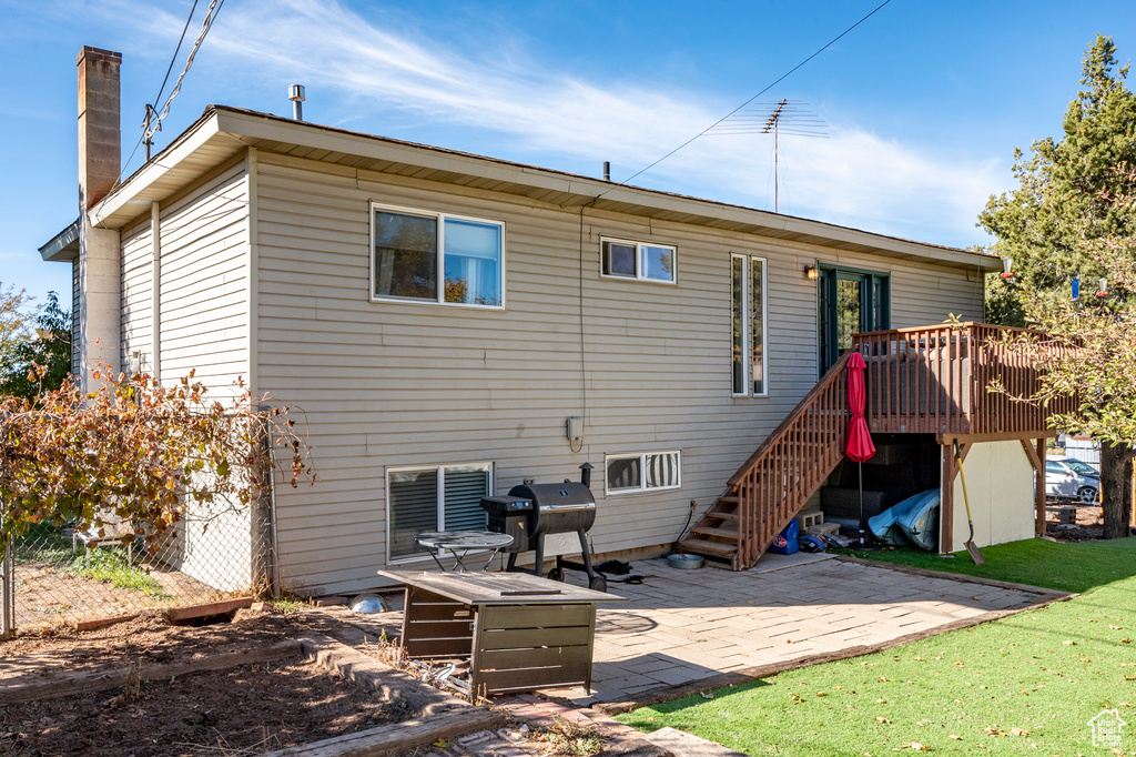 Rear view of property featuring a deck, a yard, and a patio area