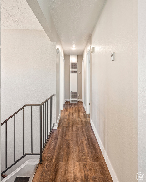 Hallway with a textured ceiling and dark hardwood / wood-style floors