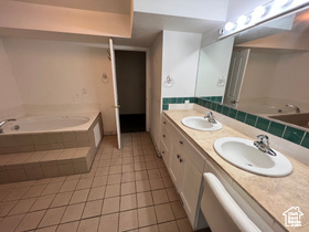 Bathroom featuring vanity, tiled bath, and tile patterned flooring