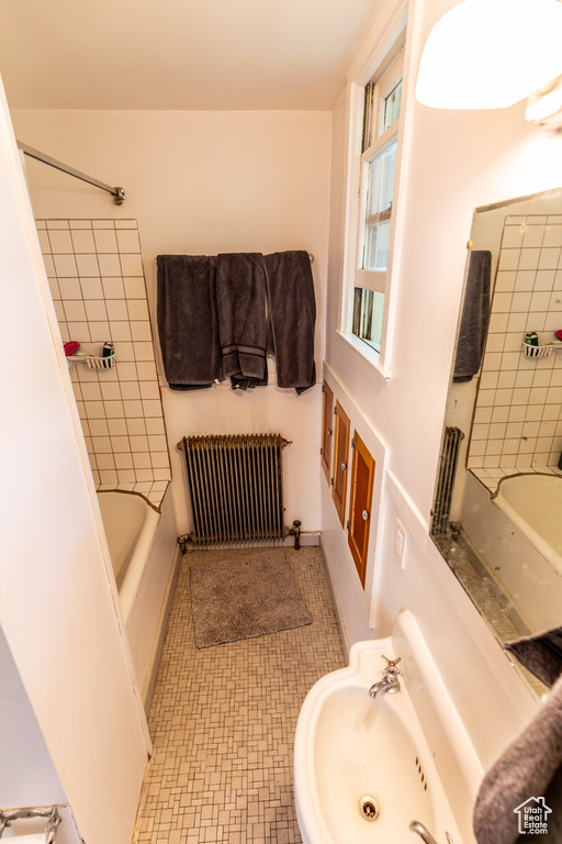 Bathroom featuring tiled shower / bath, sink, and radiator