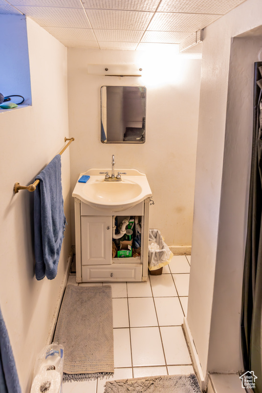 Bathroom with vanity, a drop ceiling, and tile patterned floors