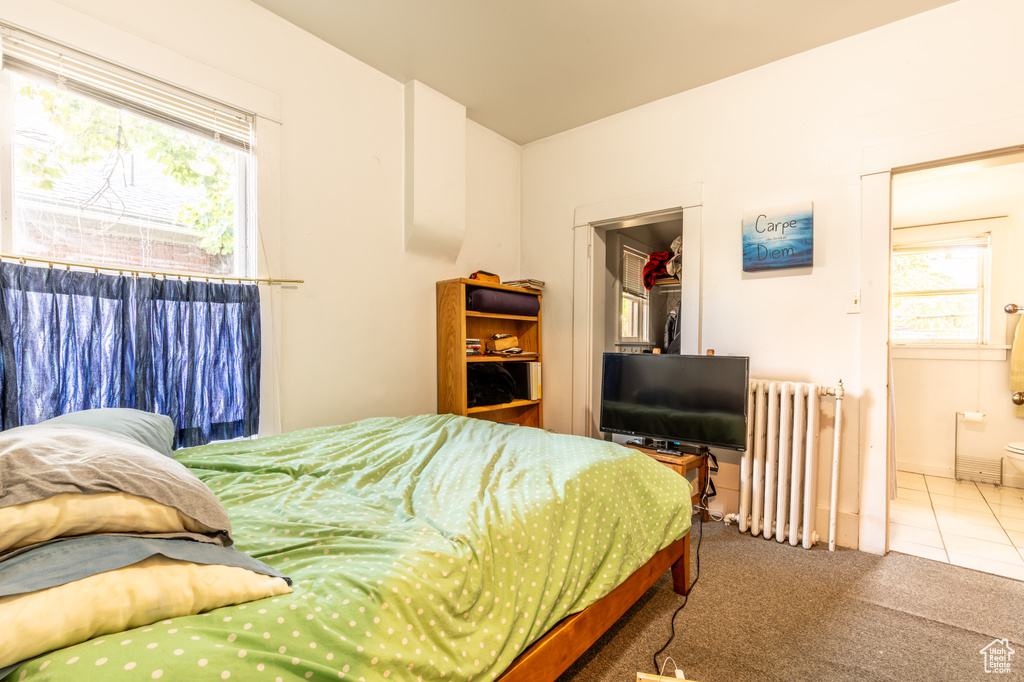 Carpeted bedroom featuring ensuite bathroom and radiator