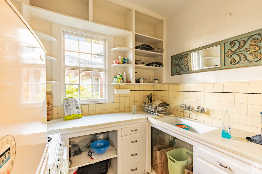 Kitchen featuring white appliances, white cabinetry, sink, and decorative backsplash