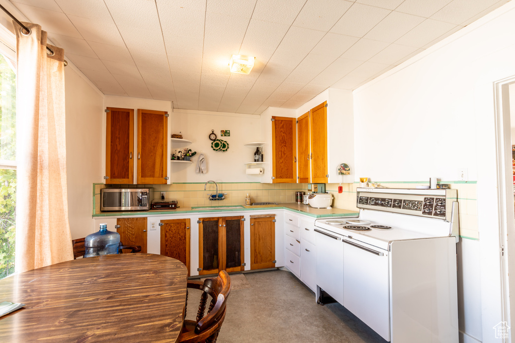 Kitchen with a wealth of natural light, sink, backsplash, and electric range