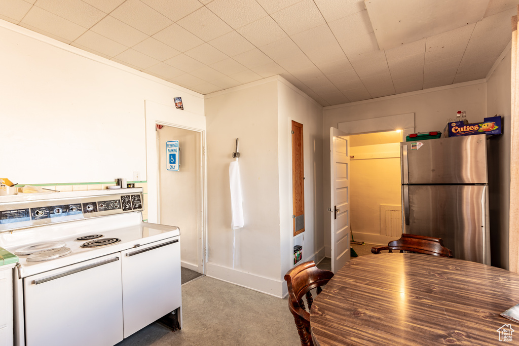 Kitchen featuring ornamental molding, white cabinetry, stainless steel refrigerator, white electric range, and light colored carpet