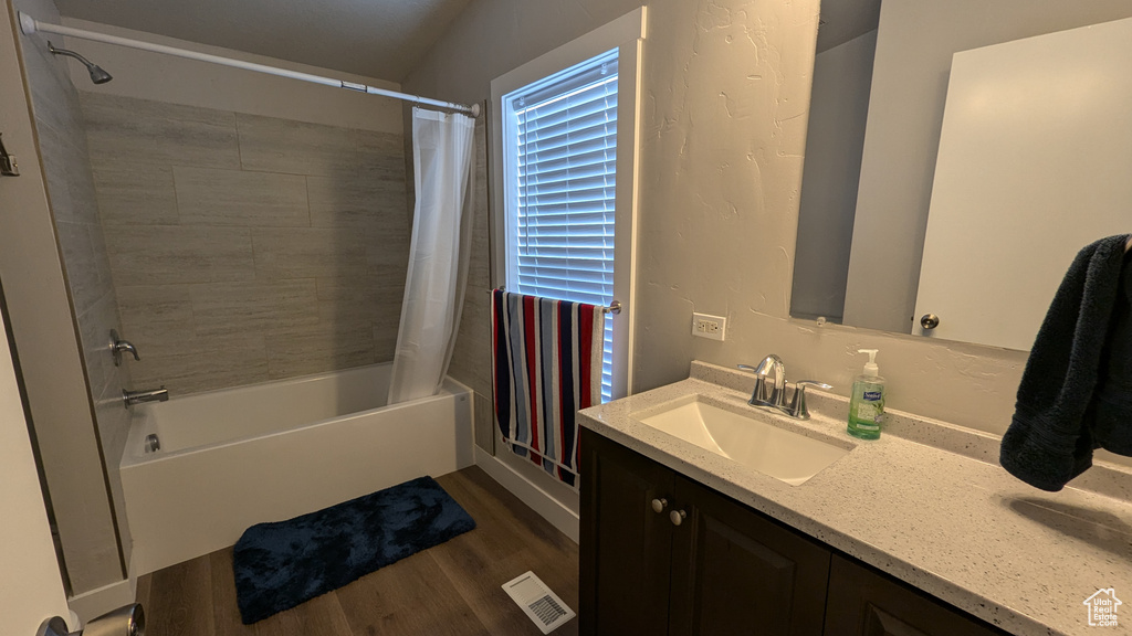 Bathroom featuring hardwood / wood-style floors, vanity, and shower / bath combo