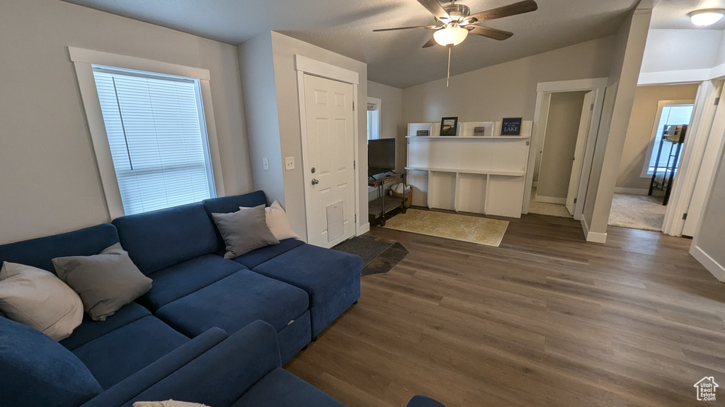 Living room with a healthy amount of sunlight, dark hardwood / wood-style floors, ceiling fan, and vaulted ceiling